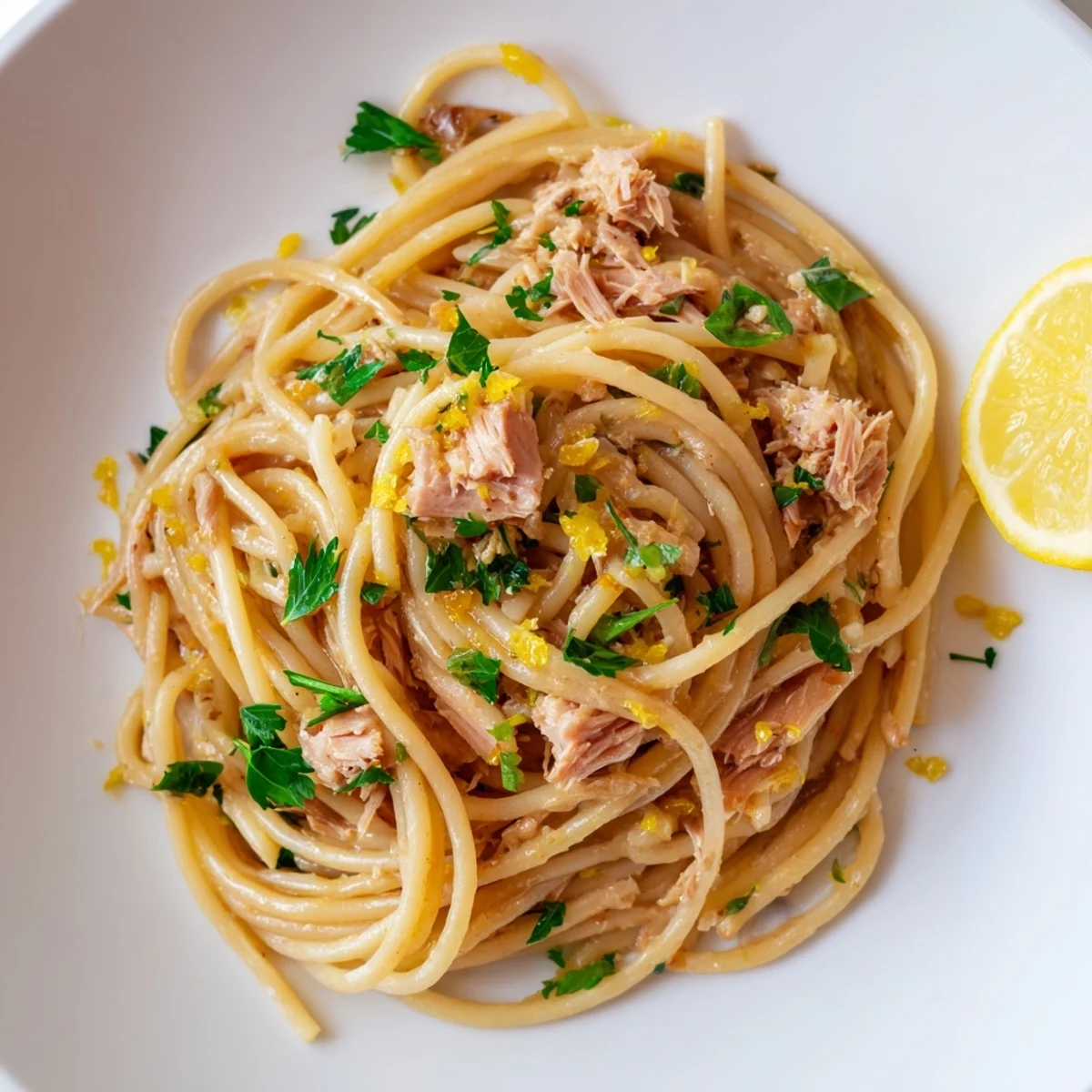 Tender spaghetti coated in a bright lemon-garlic sauce, topped with tuna for a flavorful meal.