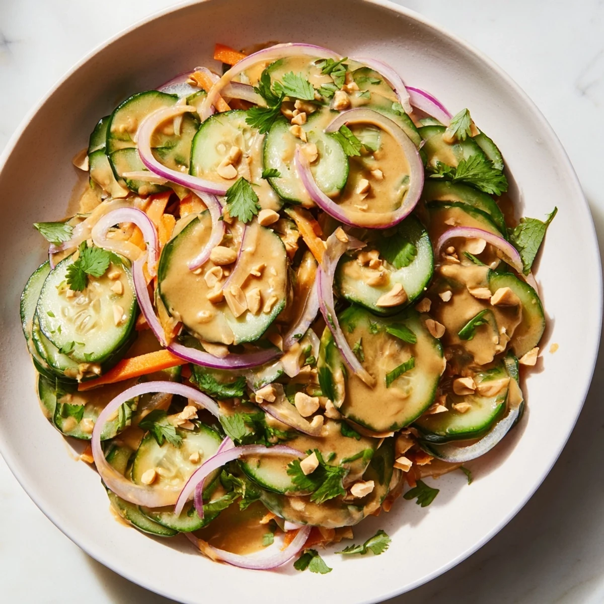 A vibrant close-up of Thai-Style Peanut Cucumber Salad, tossed in a creamy peanut dressing ready to eat.