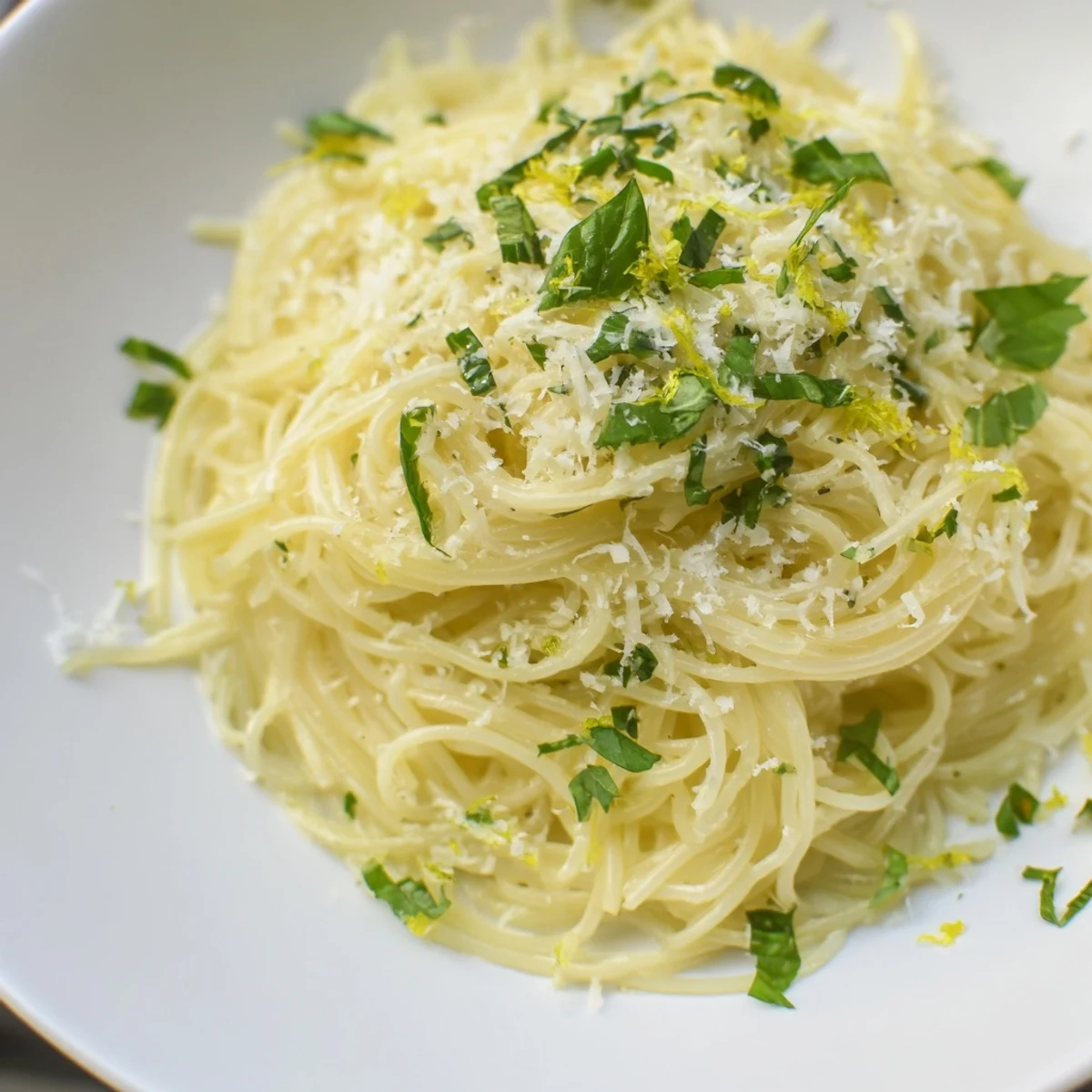 A close-up of steaming Lemon Capellini, showcasing the vibrant lemon sauce and fresh herbs.