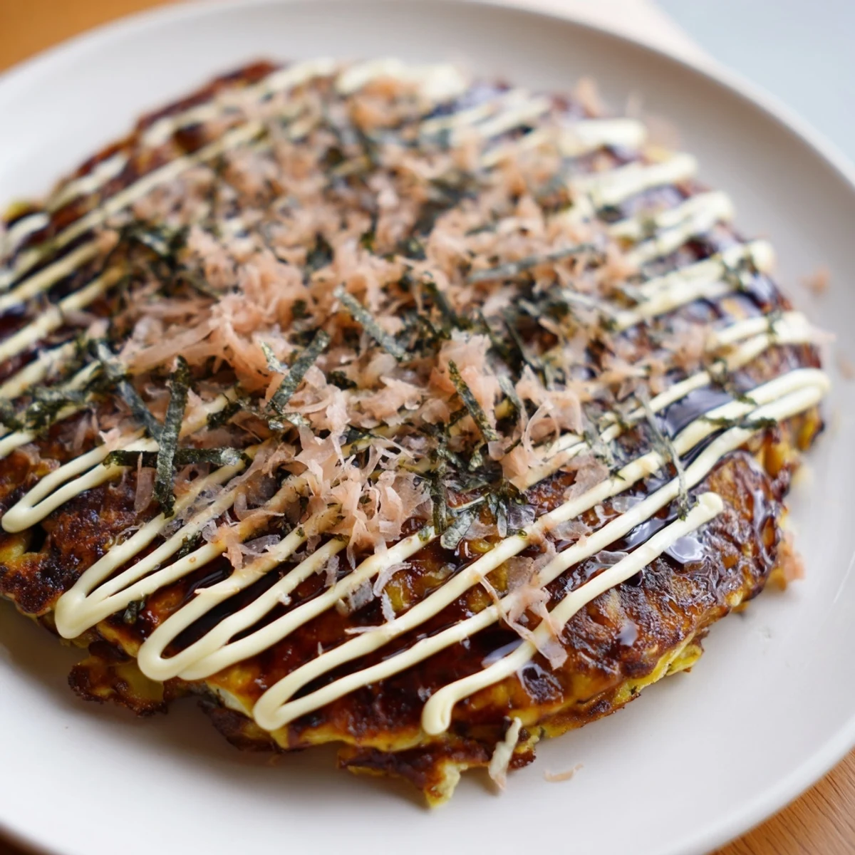 Golden-brown Japanese Okonomiyaki Pancakes topped with creamy mayo, tangy sauce, bonito flakes, and aonori.