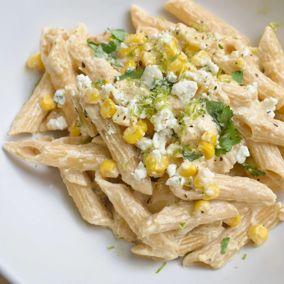 Sizzling skillet of Mexican street corn pasta with corn kernels, cotija crumbles, and a creamy lime-spiced sauce.