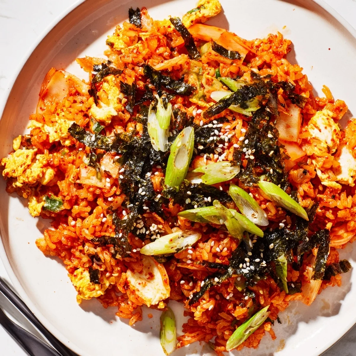 This savory vegetarian Korean-inspired main dish steams in a hot skillet, showcasing glossy, caramelized kimchi pieces and fluffy cold rice tossed in gochujang.  
