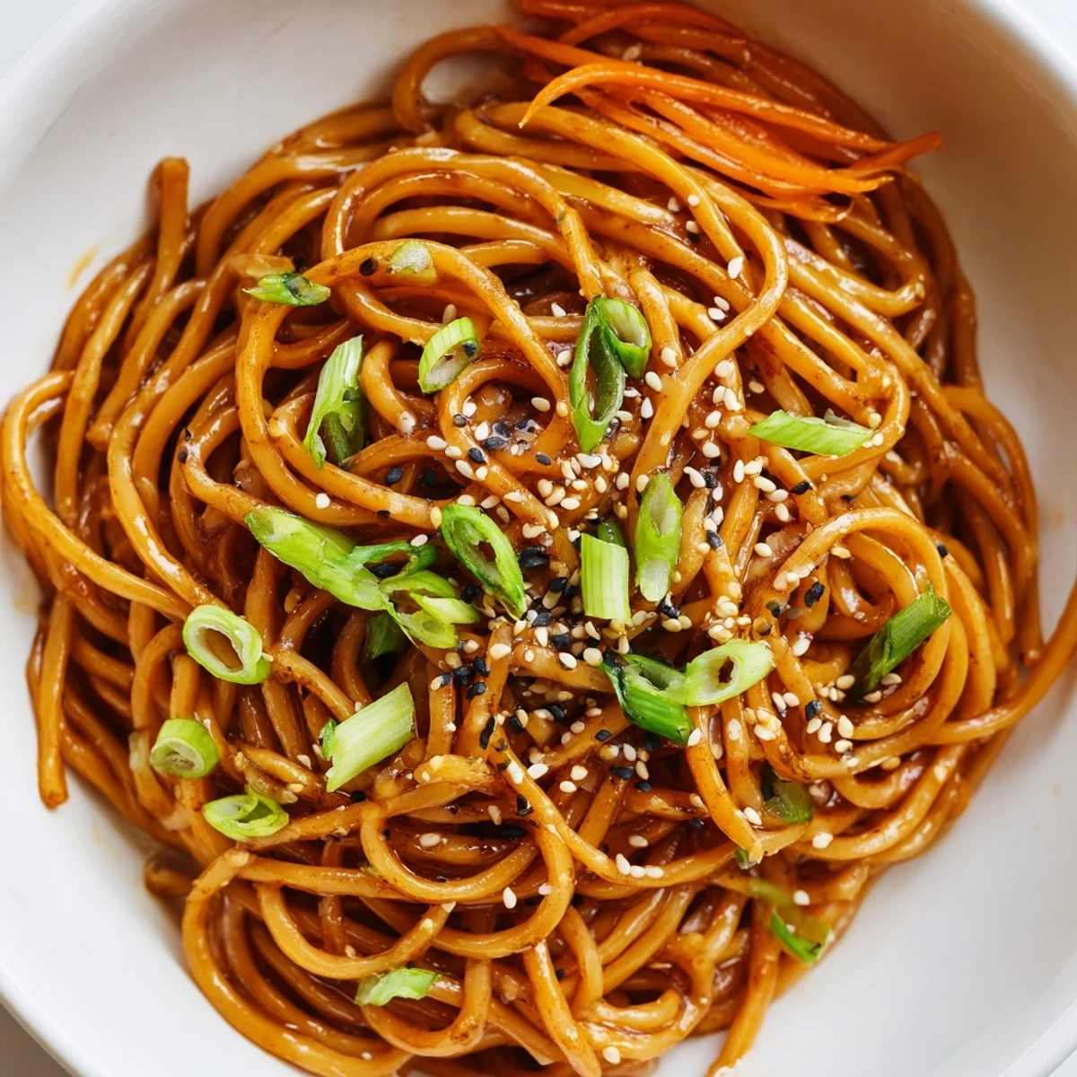 A close-up of a steaming Asian Garlic Noodle Bowl, garnished with green onions, sesame seeds, and fresh cilantro.  