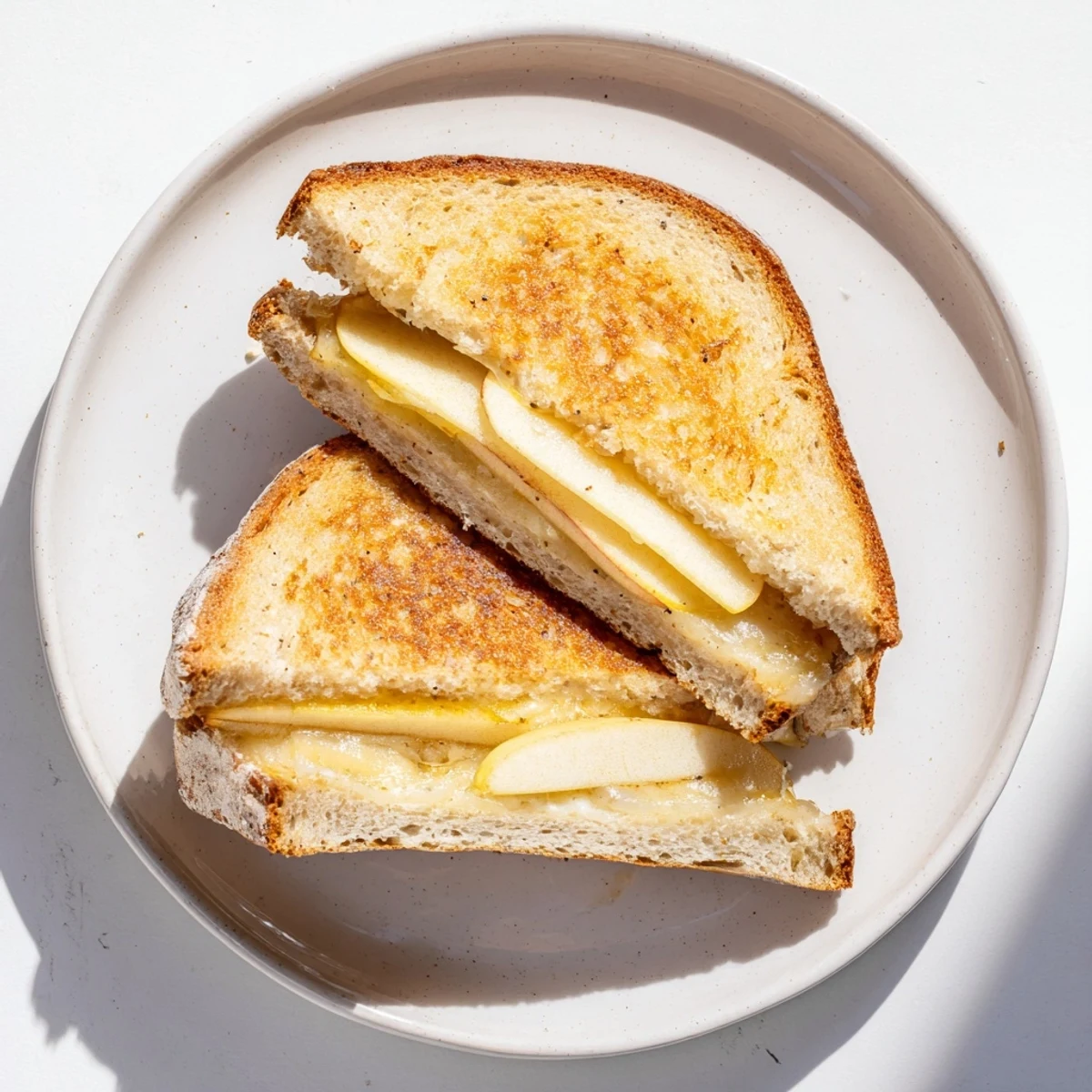 Savory and sweet smoked Gouda & apple grilled cheese, served warm beside a steaming bowl of tomato soup.