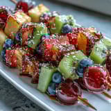 Vibrant rainbow fruit skewers featuring strawberries, pineapple, kiwi, and blueberries, paired with a creamy honey dip for a refreshing summer treat.  