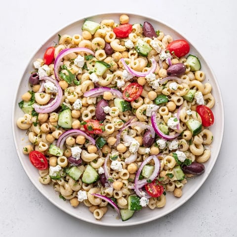 Bright, colorful Lemon Herb Chickpea Pasta Salad with diced cucumbers, cherry tomatoes, and fresh herbs in a zesty lemon dressing.  