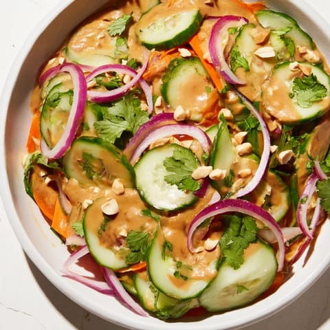Freshly prepared Thai-Style Peanut Cucumber Salad with crunchy cucumbers and a savory peanut sauce drizzle.