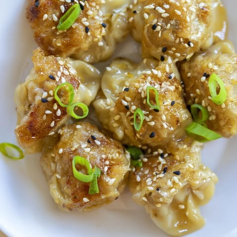 These hot and savory Air Fryer Frozen Dumplings are pictured with a sesame seed garnish, perfect snack.