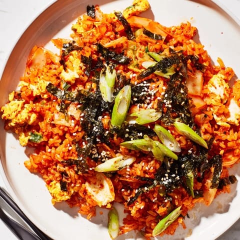 This savory vegetarian Korean-inspired main dish steams in a hot skillet, showcasing glossy, caramelized kimchi pieces and fluffy cold rice tossed in gochujang.  