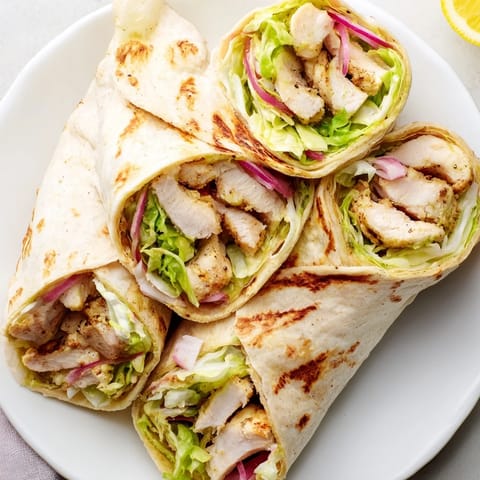 Freshly sliced tomatoes and red onion add crunch to this easy homemade Honey Mustard Chicken Wrap, served warm on a rustic plate.