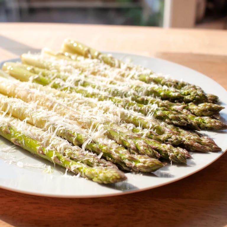 Vibrant green roasted asparagus topped with Parmesan and lemon, a simple Mediterranean side.