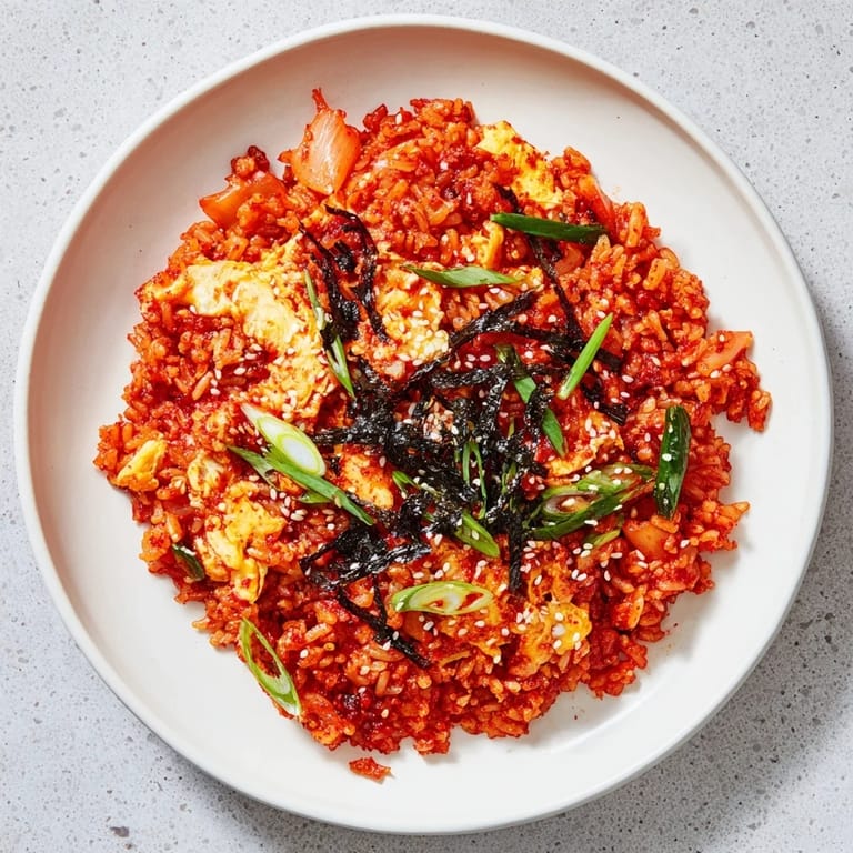 Served in a rustic ceramic bowl, the aromatic kimchi fried rice is topped with crispy roasted seaweed strips and a drizzle of sesame oil.